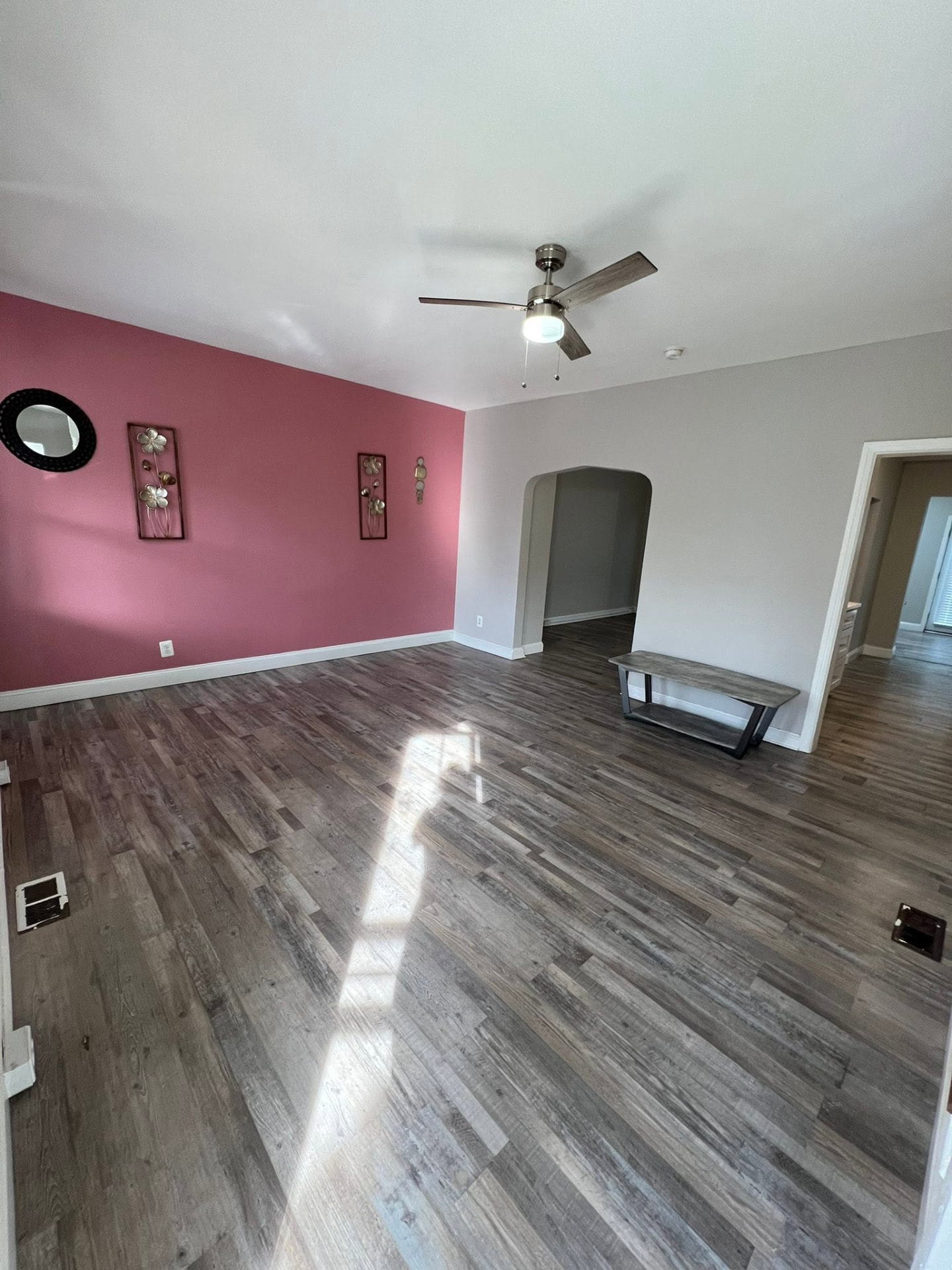 Living room with rose accent wall and new plank flooring