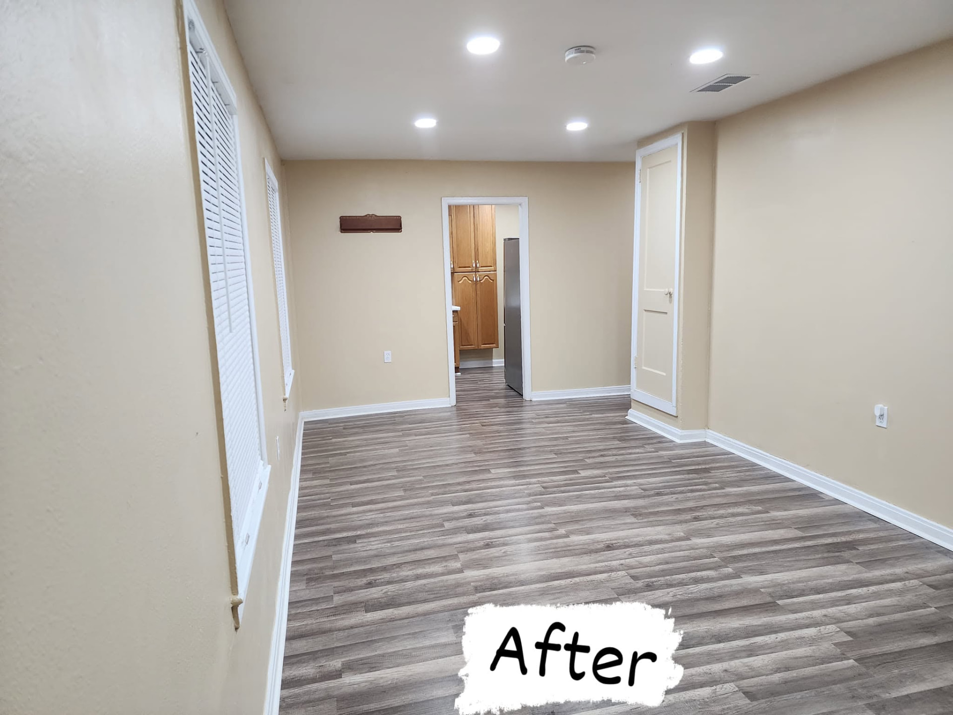 Back room after: bright walls, new flooring running through to the kitchen and clean trim