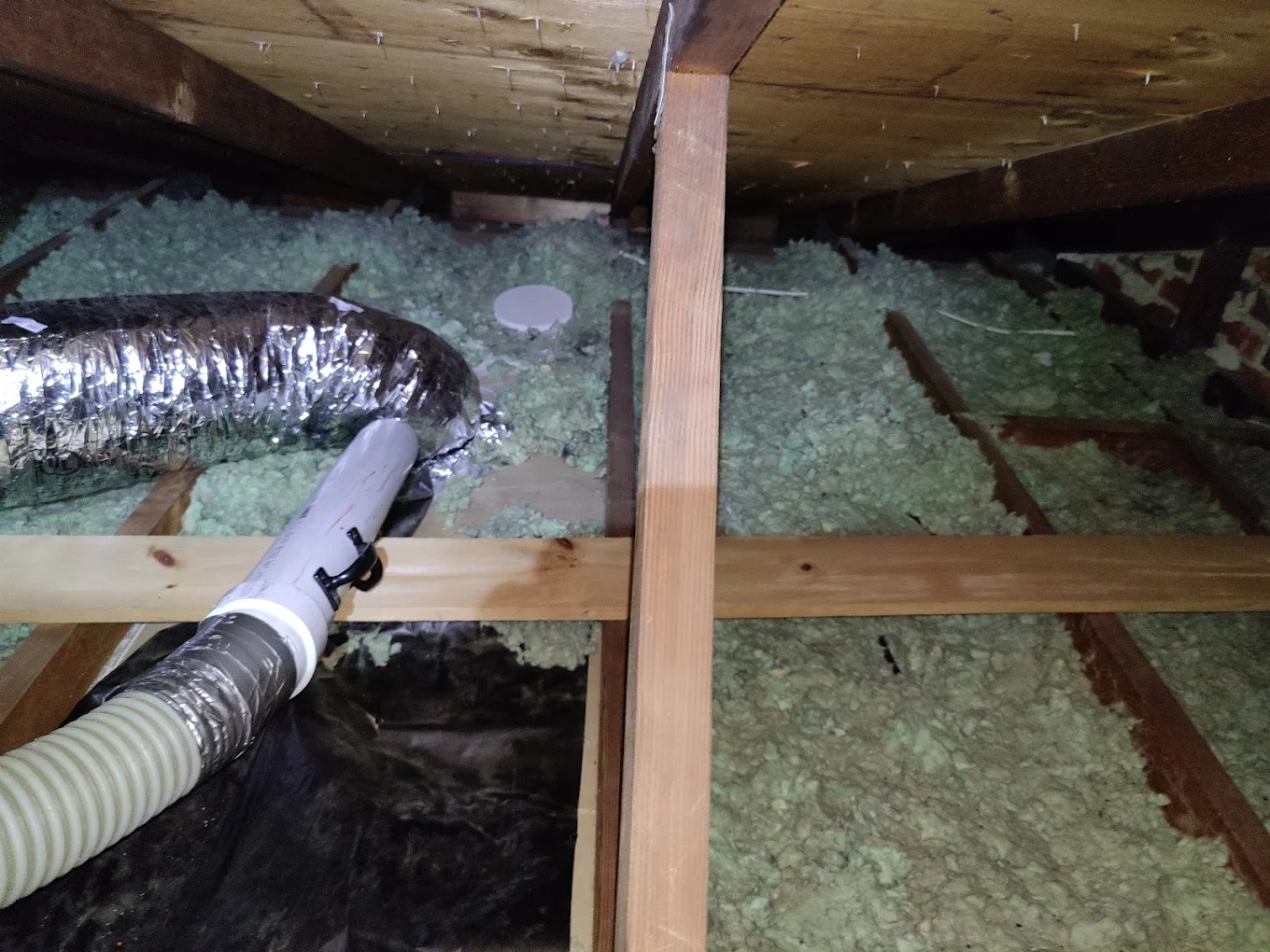 Attic ductwork and insulation hose running across the joists mid-install