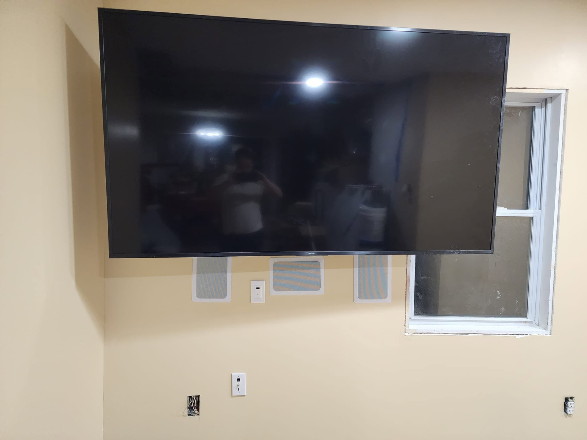 TV flush-mounted on a wall with in-wall speakers and hidden wiring