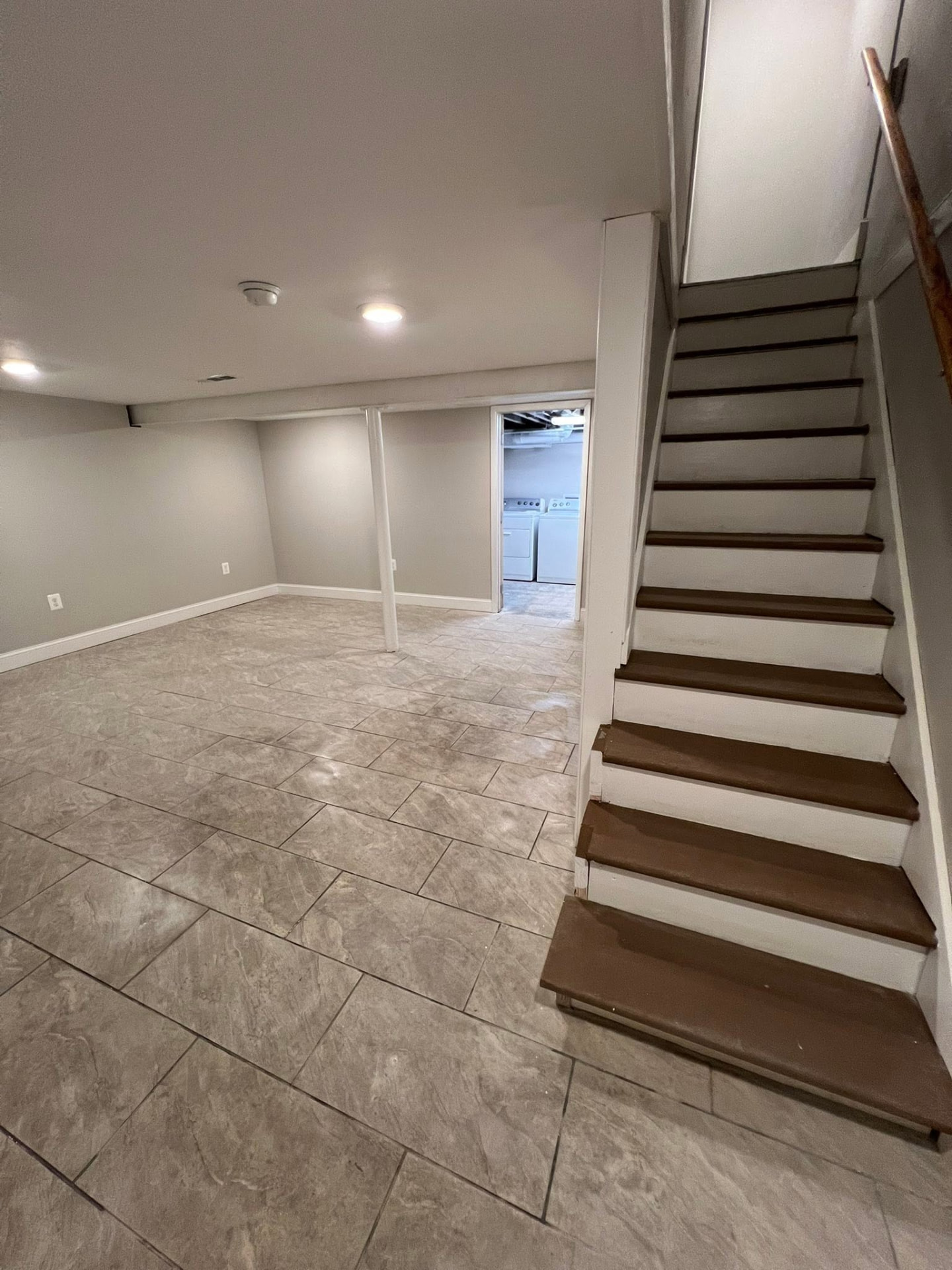 Finished basement with repainted stairs and tile floor