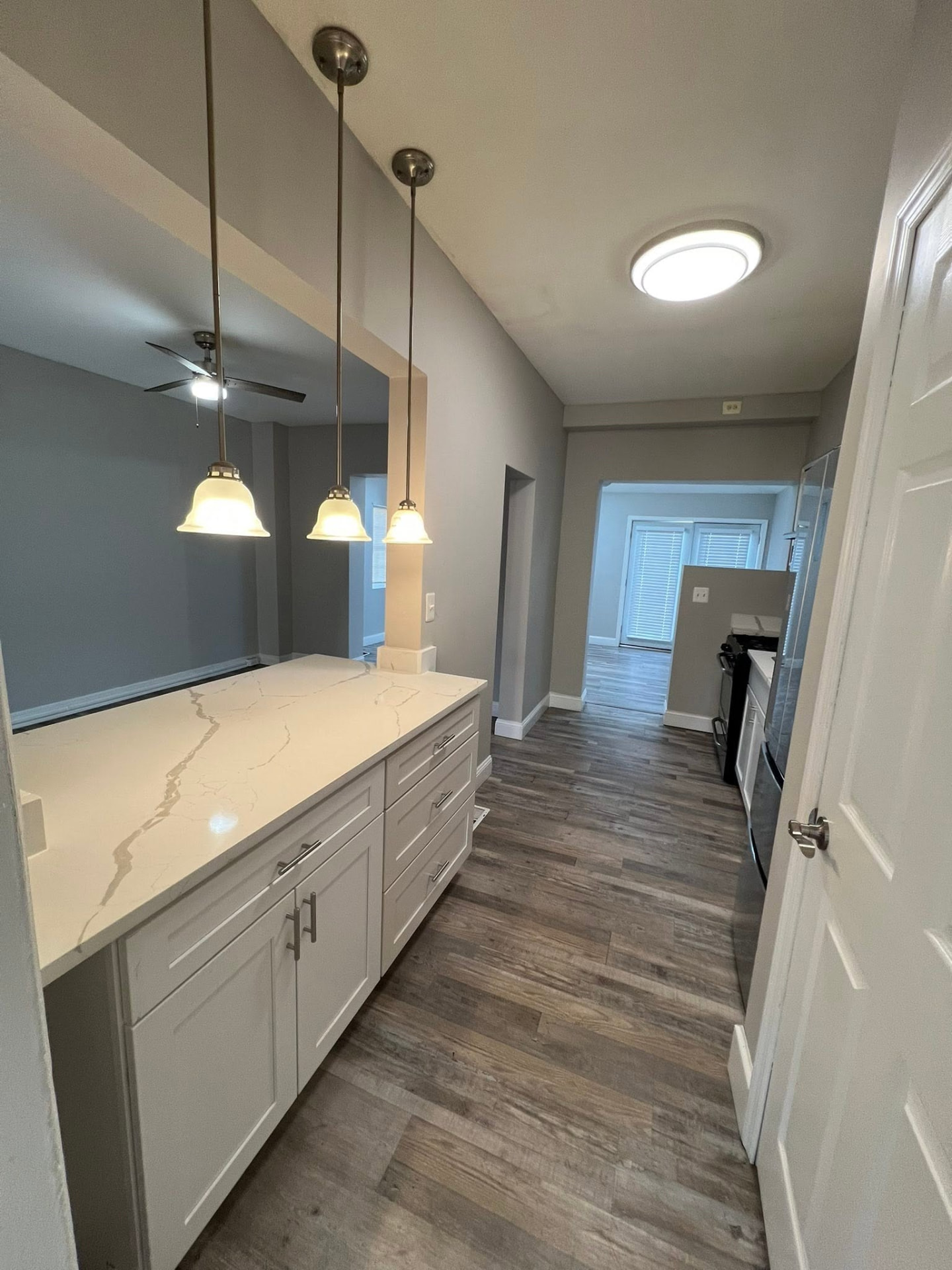 Quartz breakfast bar with pendant lights looking down the hallway