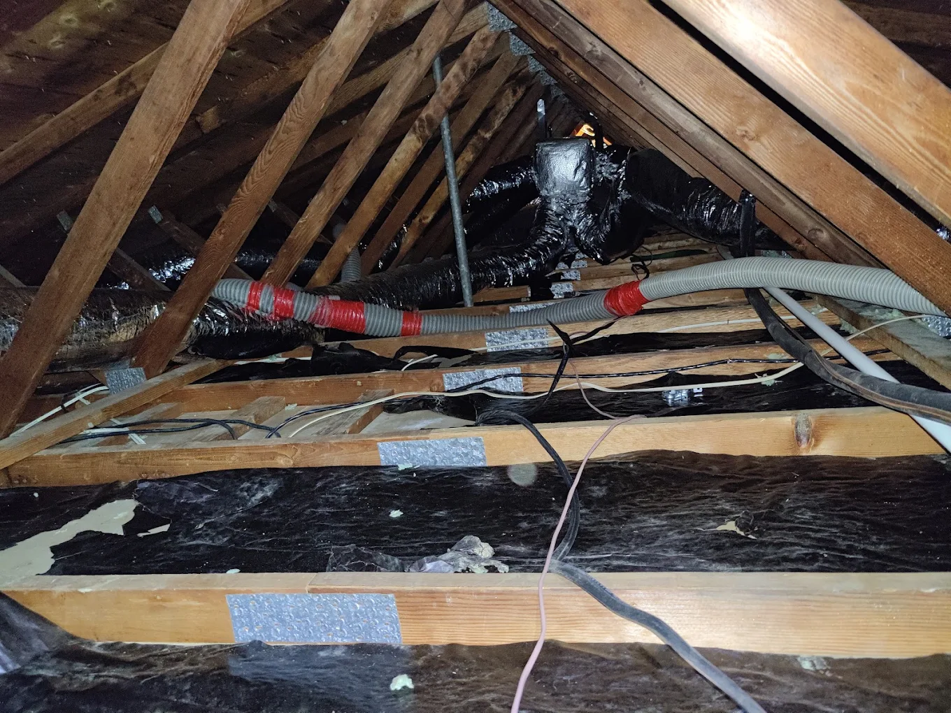 Attic ducts, wiring and old insulation before remediation