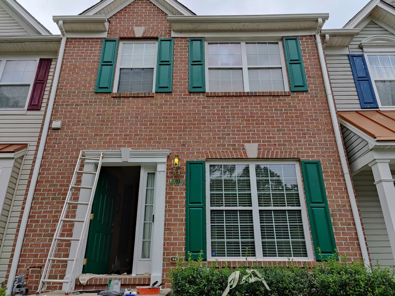 Brick townhome exterior with freshly painted green door and shutters