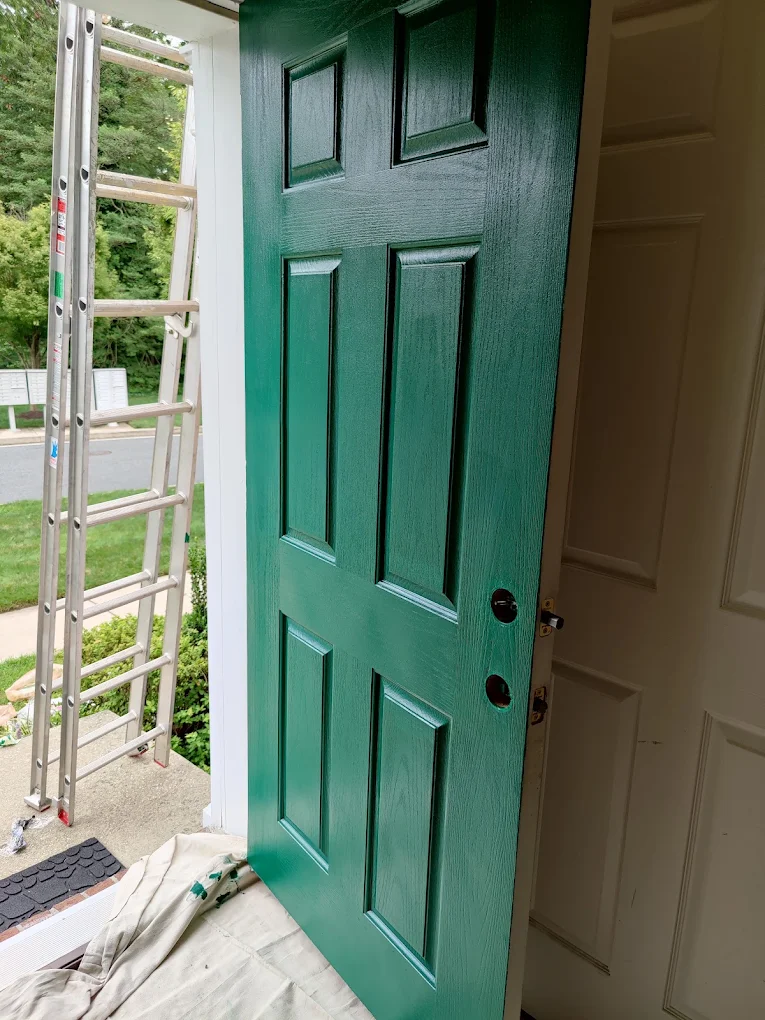 Freshly painted deep green front door with drop cloths down